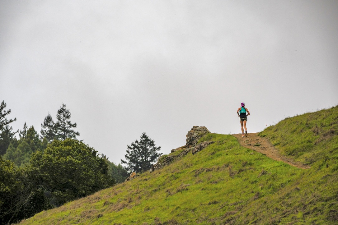 Runner ascending grassy hillside ridge
