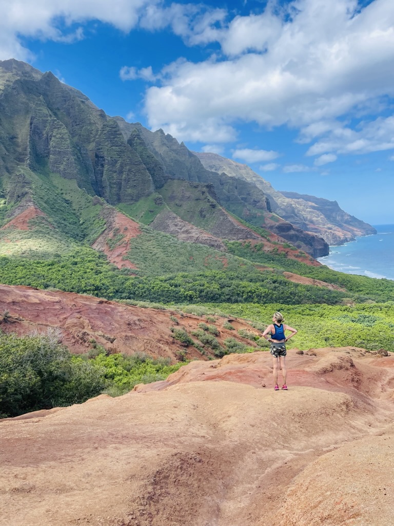 Trail runner viewing Na Pali Coast cliffs in Hawaii