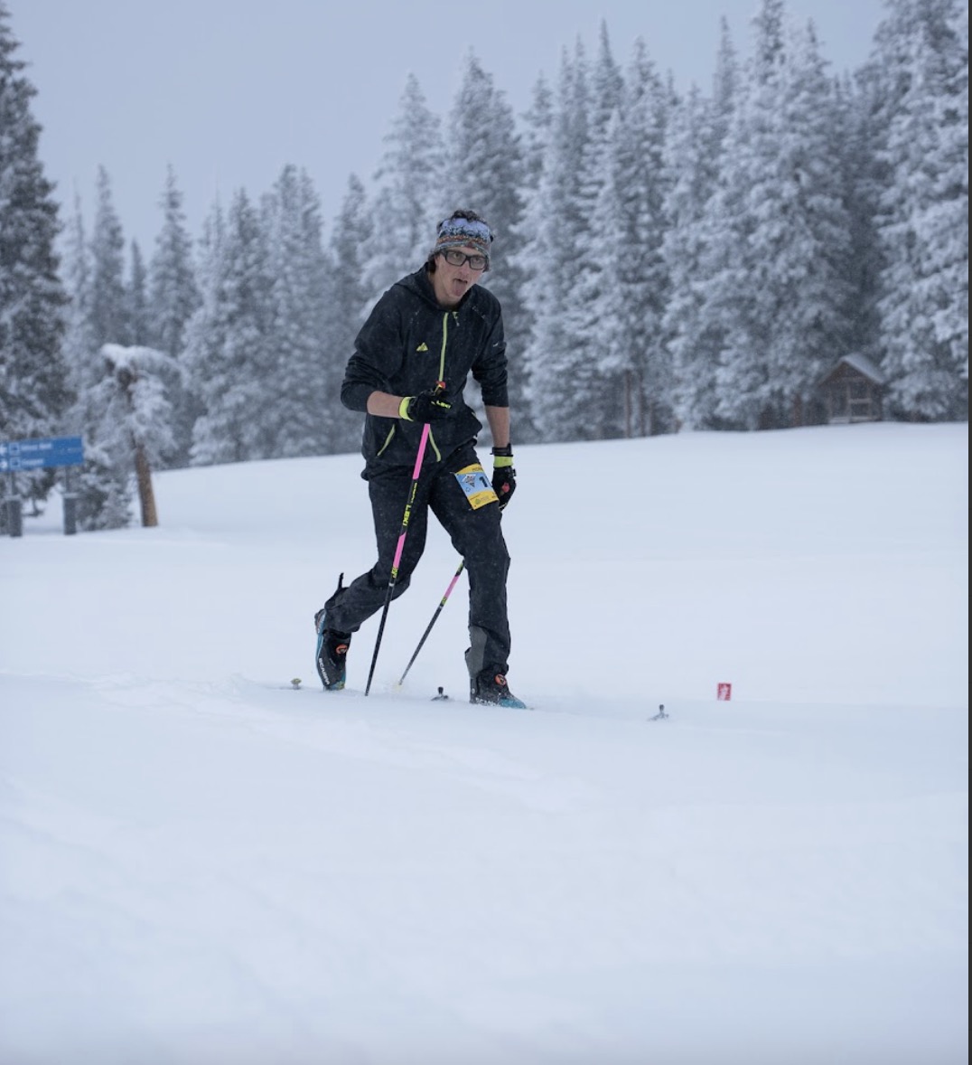 Solo skimo racer skiing across flat snowy terrain on an overcast day